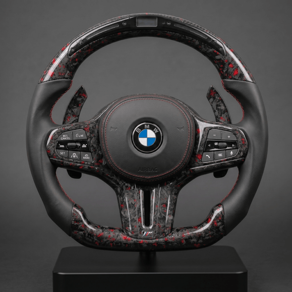 Custom BMW G Series steering wheel in forged carbon with red flecks, perforated leather grip and red stitching, shown on a stand