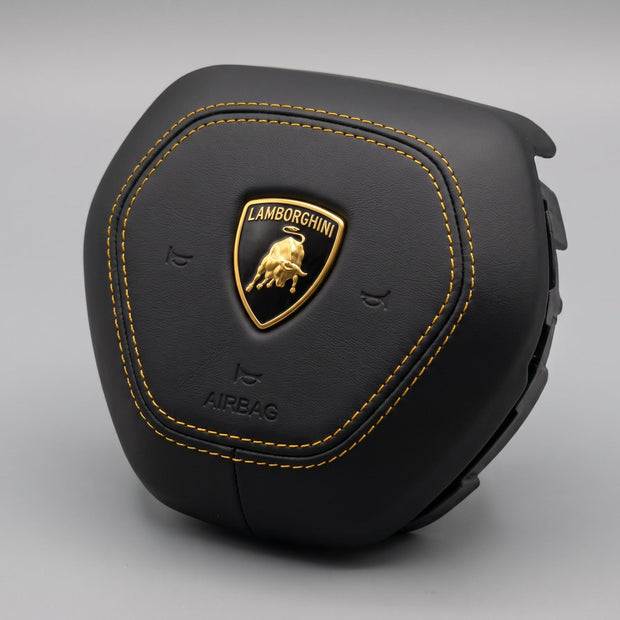 Tampa do airbag Lamborghini Urus 2018-2026 em pele preta lisa com costuras amarelas, vista de três quartos