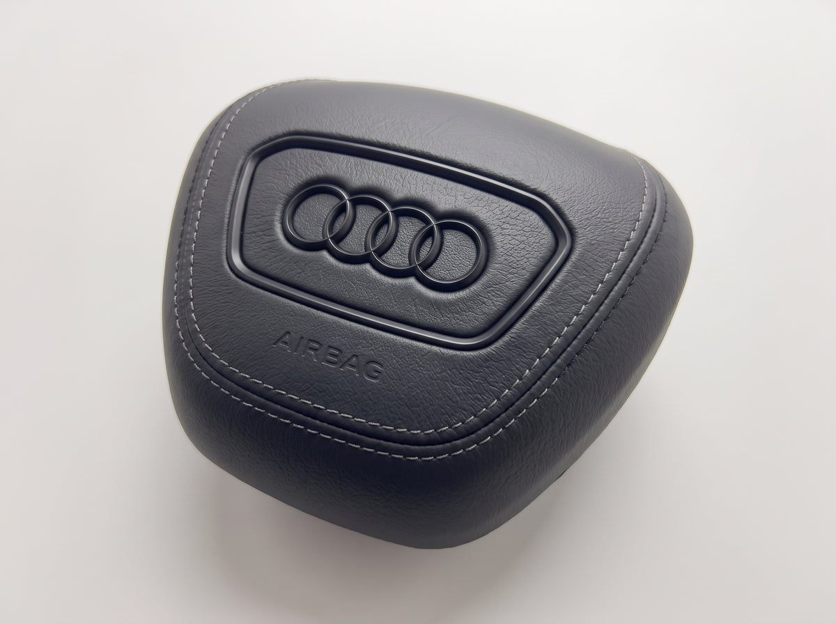 Tampa do airbag Audi 2022-2024 em pele preta lisa, vista de três quartos