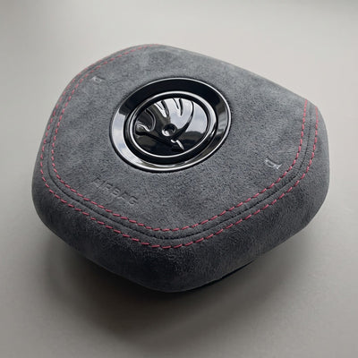 Tapa del airbag de Alcantara gris con costuras rojas Skoda Fabia IV Octavia IV vista de tres cuartos